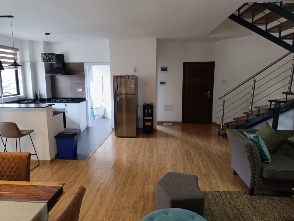 Partial view of the open plan kitchen with a fridge in a furnished duplex apartment for short stay in Kilimani