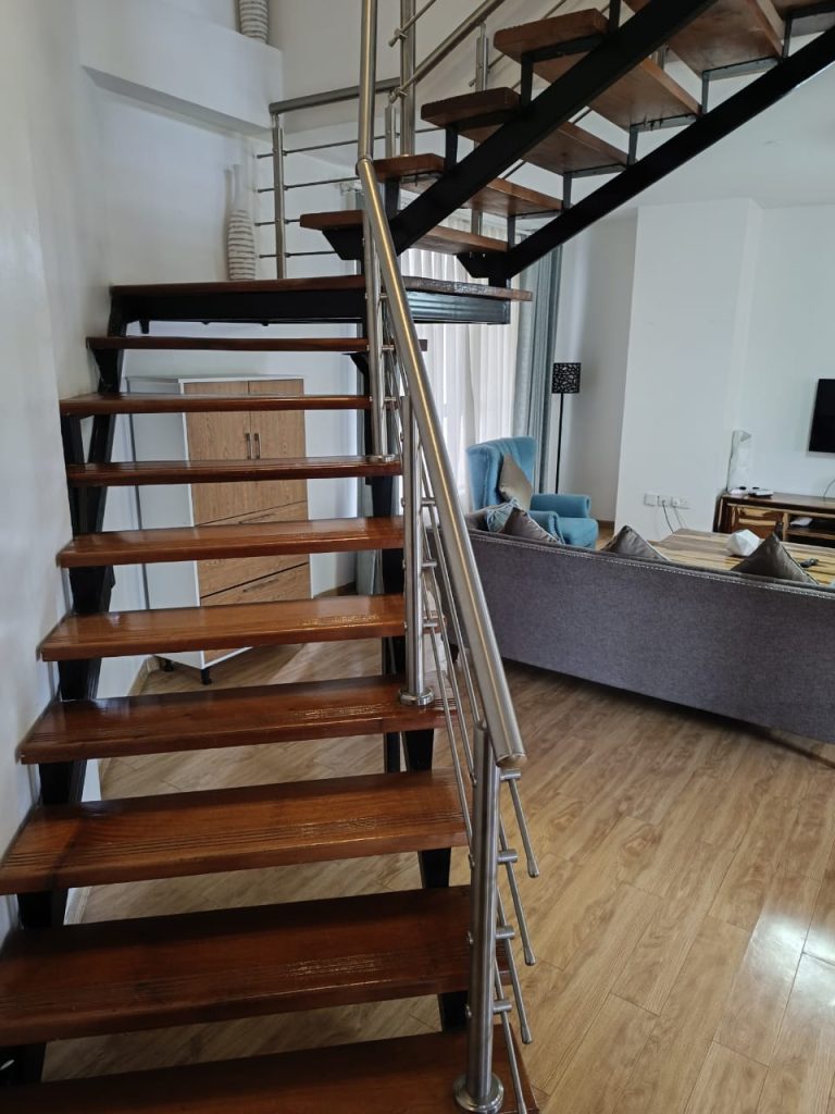 Staircase inside a furnished duplex apartment for short stay in Kilimani with partial view of the modern living room