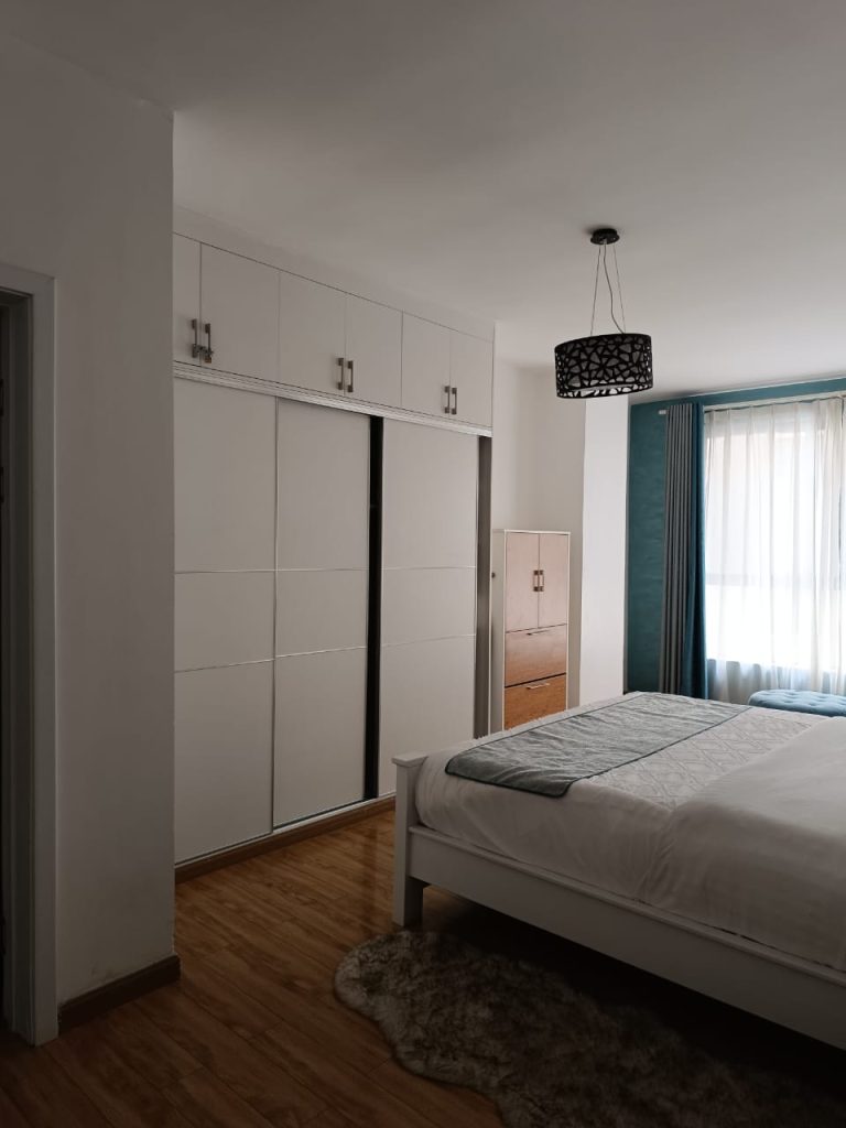 Large bedroom with sleek white fitted wardrobes – Serviced 2 Bedroom Duplex Apartment in Nairobi