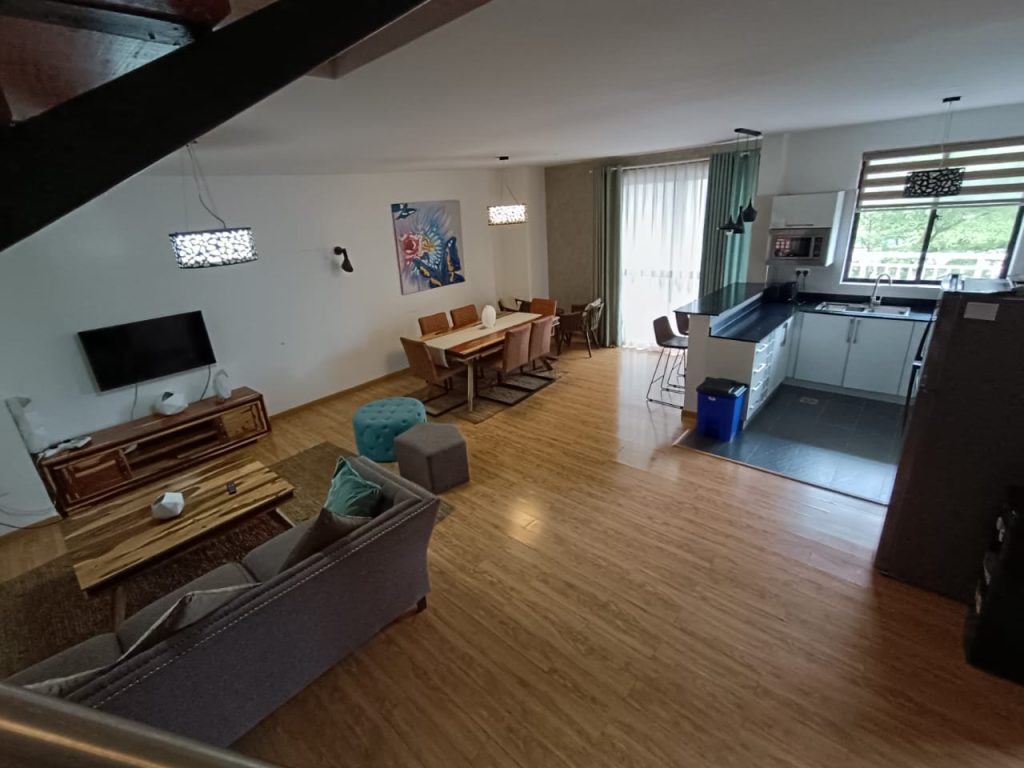 Spacious lounge area with partial view of the open plan kitchen in a Kilimani furnished duplex apartment