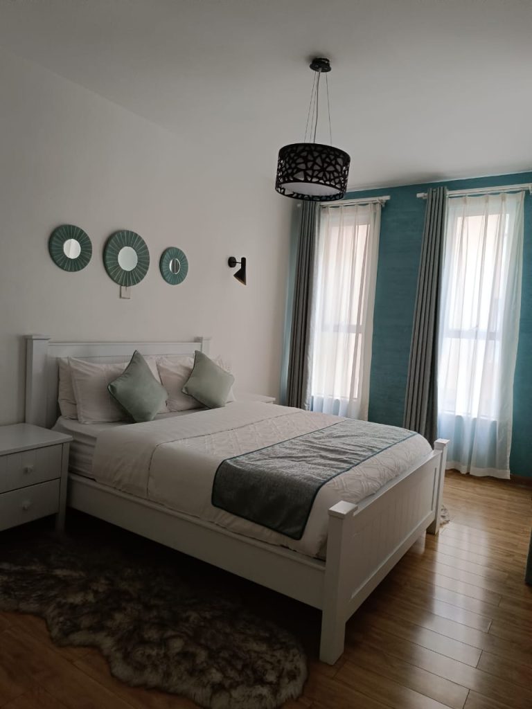 Queen size bed and well-lit bedroom with large windows – Serviced 2 Bedroom Duplex Apartment in Nairobi
