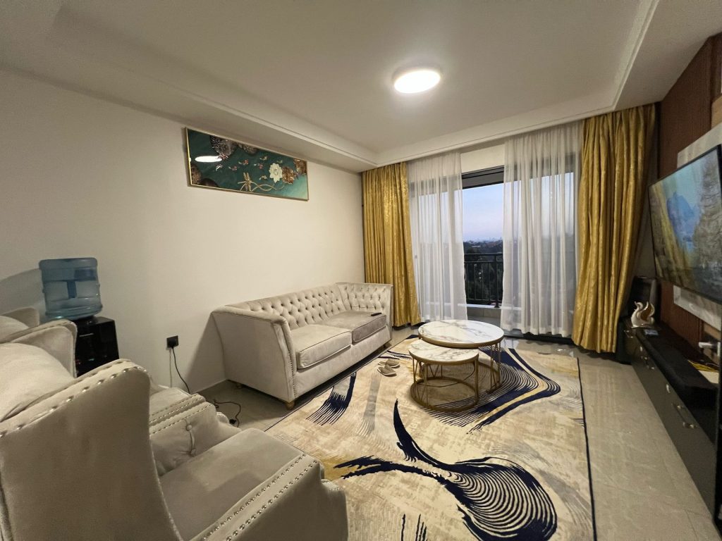 Bright seating area at Ruaka furnished daily and monthly rental in Nairobi with large windows, a two-seater, and two single couches partially visible.