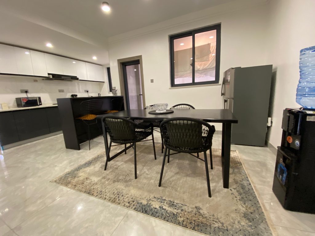 Elegant dining area with open plan kitchen view in a fully furnished 2 bedroom master ensuite.