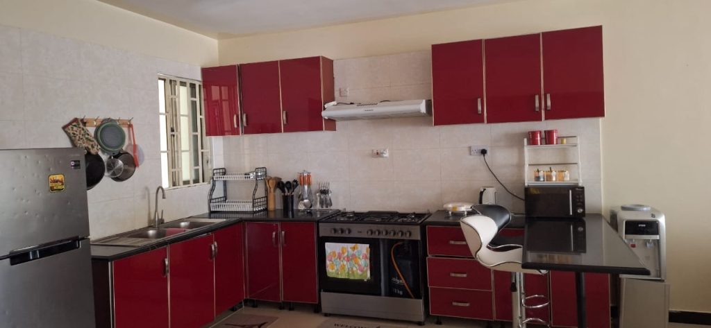 Fully equipped open plan kitchen with built-in cooker, hood, and modern cabinetry – Luxury 3 Bedroom Serviced Apartment in Nairobi