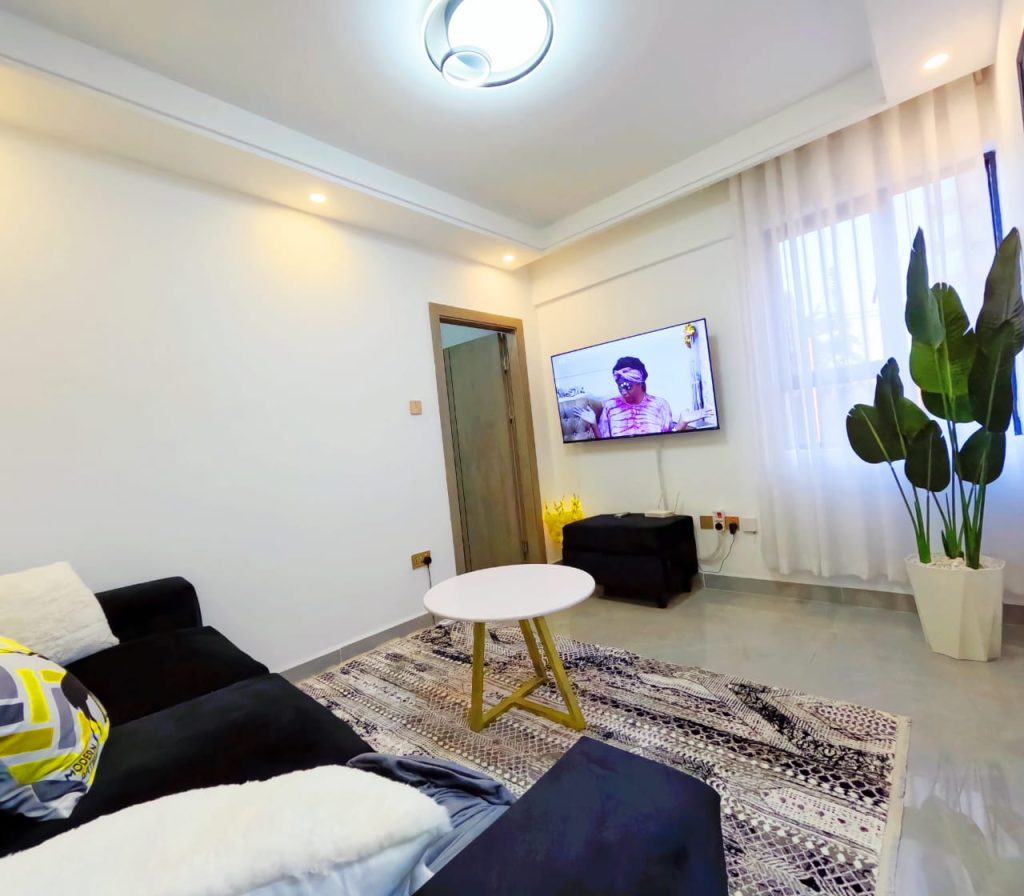 Living area featuring a smart TV and large windows that let in natural light in a serviced furnished 1‑bedroom apartment in Lavington.