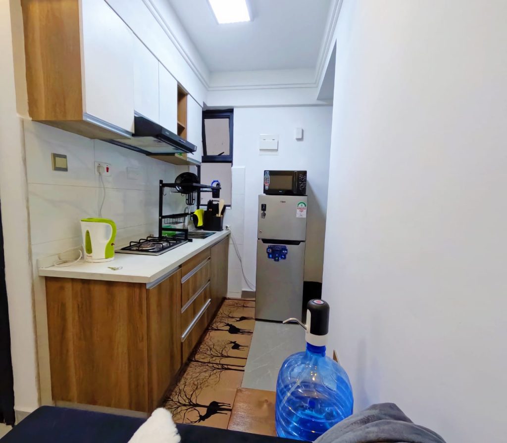 Modern open plan kitchen showing full cabinetry and built-in appliances in a serviced furnished 1‑bedroom apartment in Lavington.