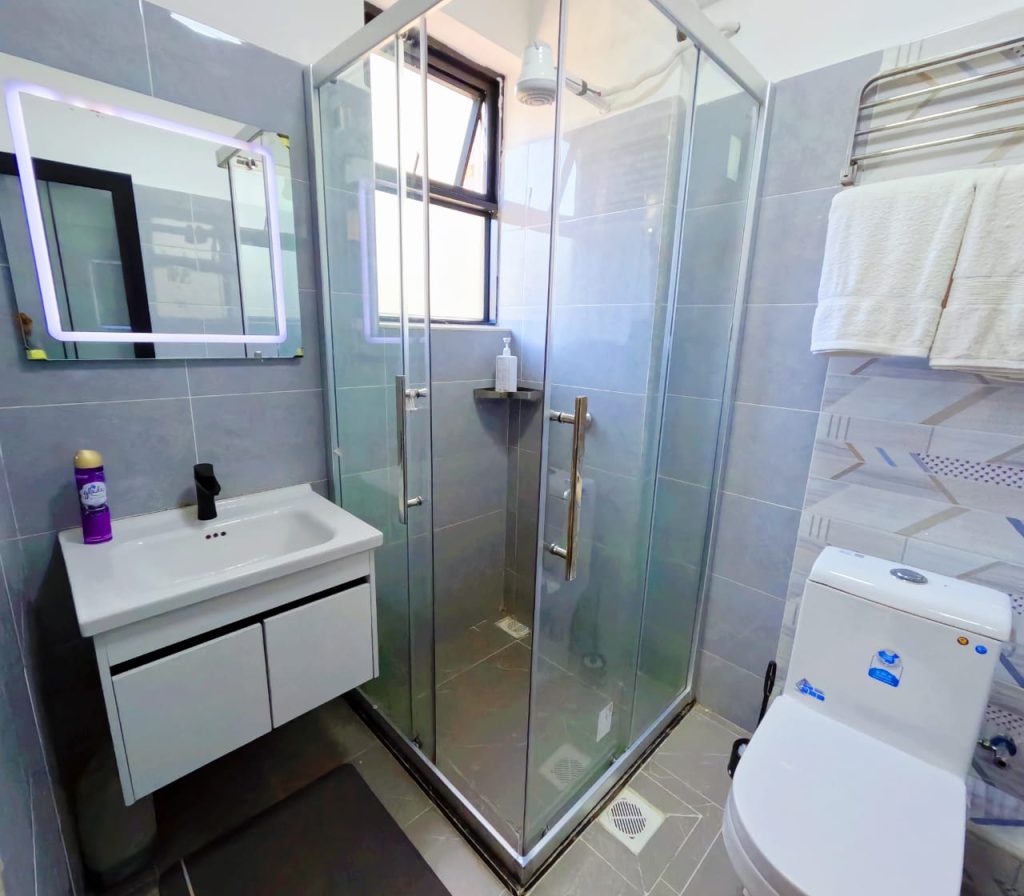 Tiled bathroom with cubicle shower, toilet, and sink inside a serviced furnished 1‑bedroom apartment in Lavington.