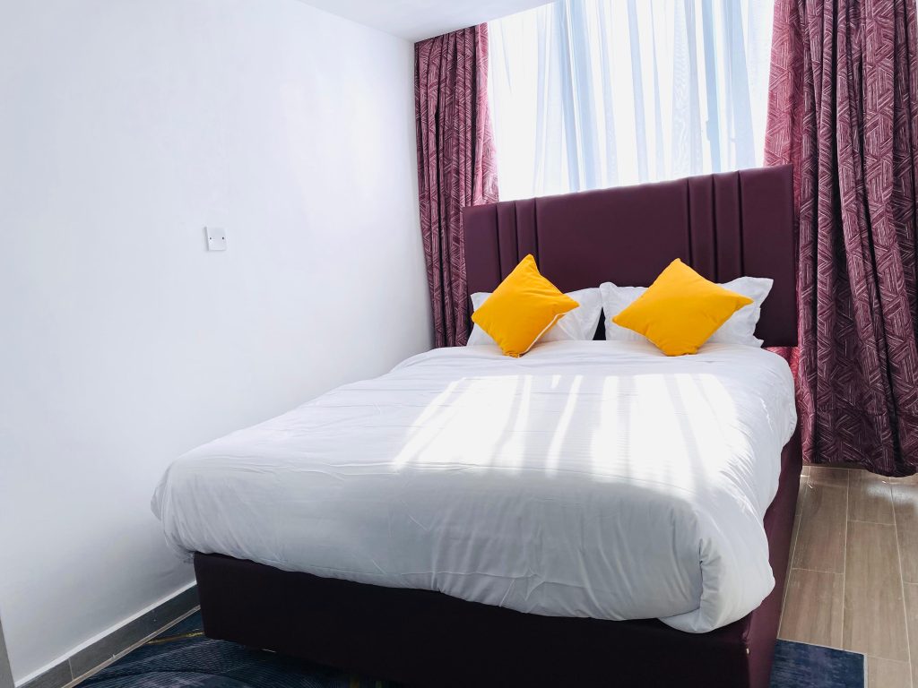 Cozy queen-size bed with white duvet and clean bedding inside an affordable 1-bedroom furnished apartment in Nairobi.