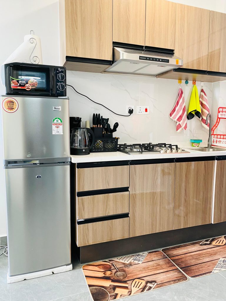 Modern open-plan kitchen fitted with storage cabinets in an affordable 1-bedroom furnished apartment in Nairobi.