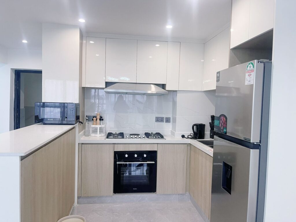 an open plan kitchen fitted with cabinets and appliances at the 2 bedroom furnished apartmaent near juction mall