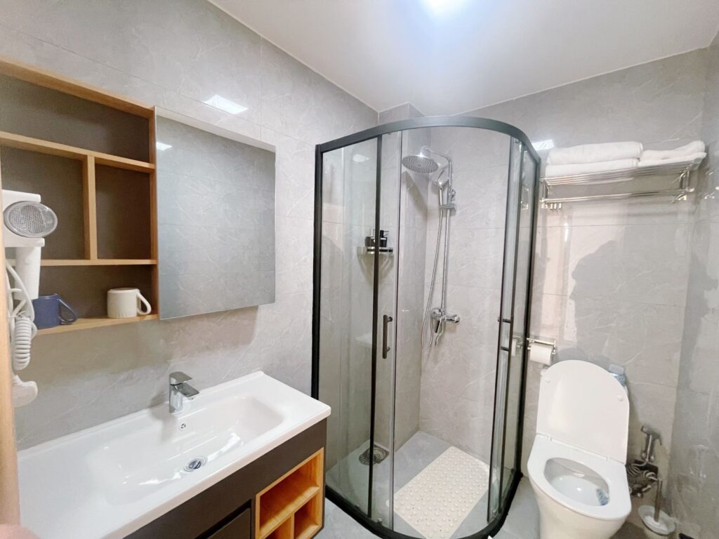 cubicle glass shower ,at toilet and a sink with a cabinet oon top at the dining area set for four at the 2 bedroom furnished apartment near juction mall