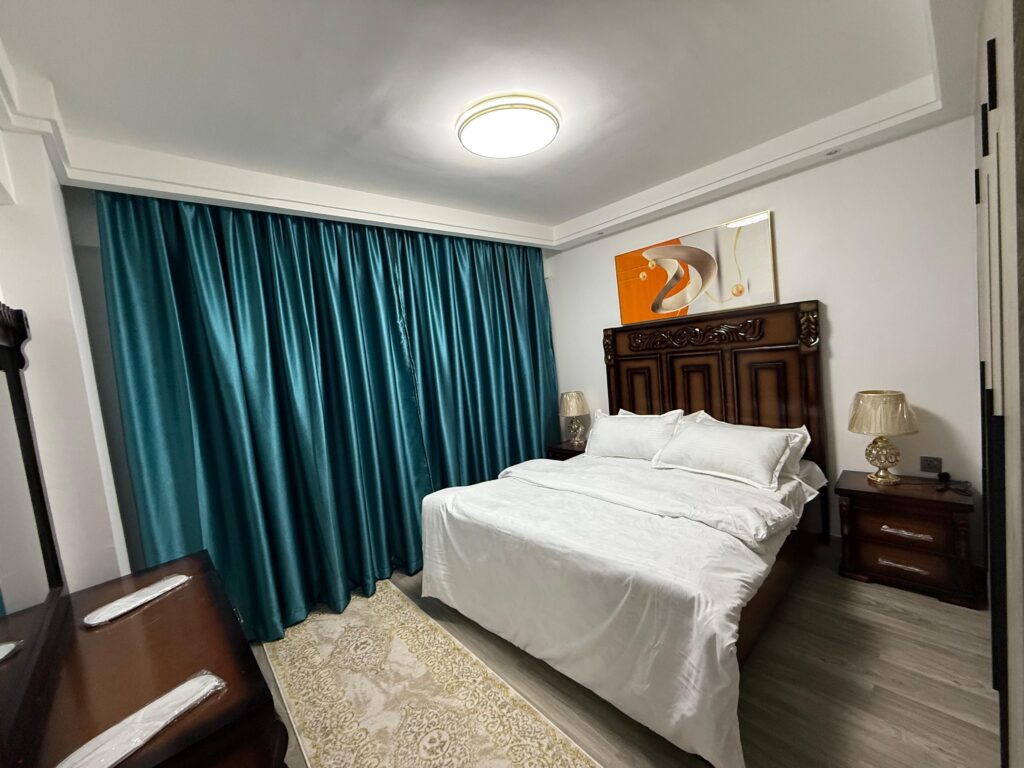 bedroom with kingsize classy bed and big windows covered with a curtain at Furnished Apartment at Alina Harbour Kilimani