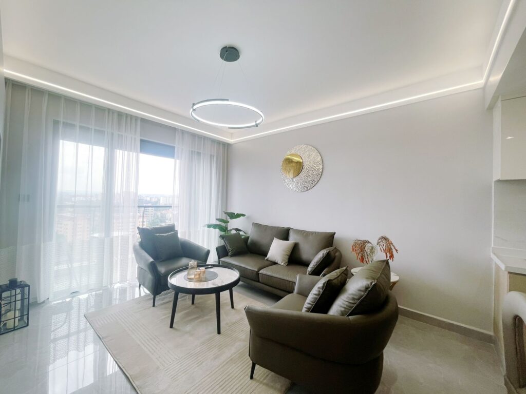The living area at Furnished apartment on riara road with sofas,a medium table and a nice mat
