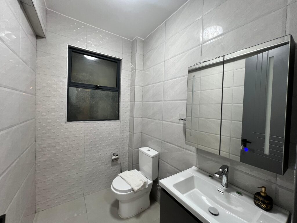 bathroom with a toilet and a sink with a mirror inside Isra Residency Parklands