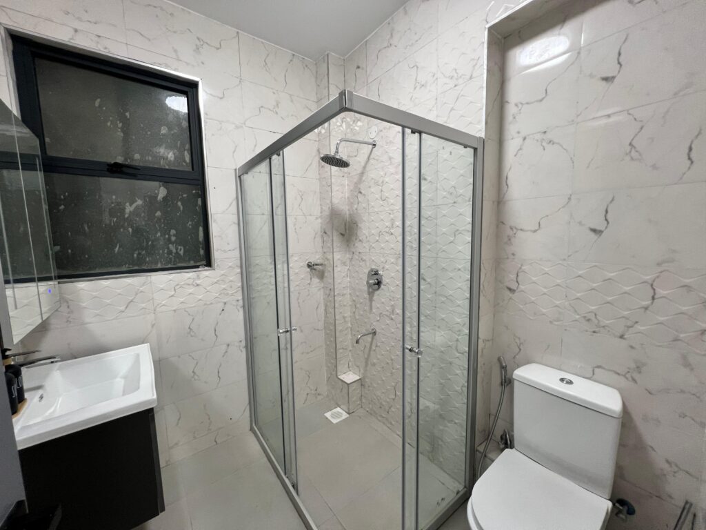 cubicle glass shower, a toilet and a sink in a bathroom at Isra Residency Parklands