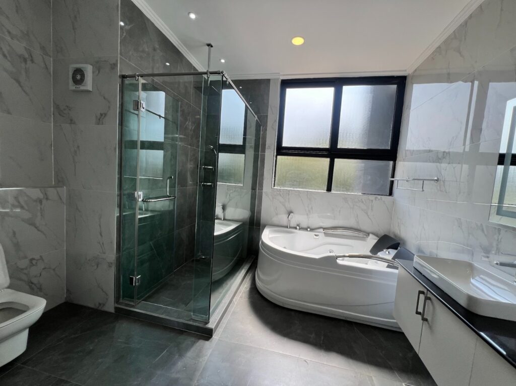 A large bathroom with glass cubicle shower, a bathtub,a toilet and a large sink with a mirror at Silver Decks Apartment