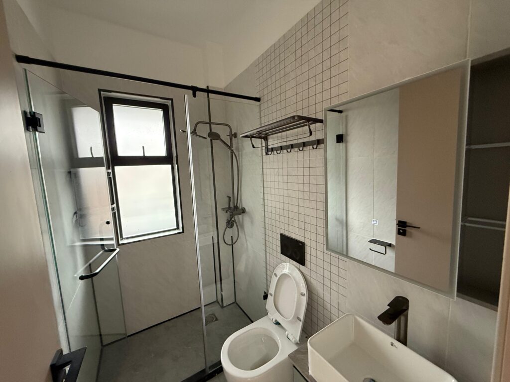 bathbathroom at 1 Bed Apartment near One Padmore Place, Kilimani room at the Unfurnished 1 Bedroom Apartment at Oak Classic with cubicle glass shower, a toilet and a sink with a mirror at Unfurnished 1 Bedroom Apartment at Oak Classic