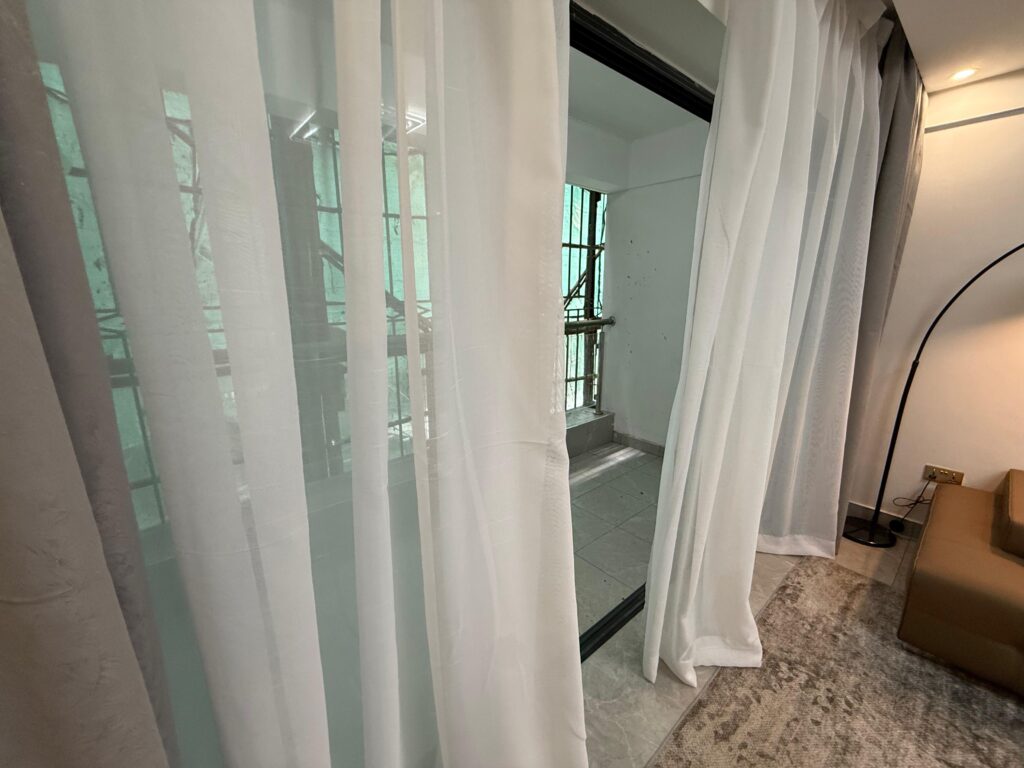 Large windows covered with transparent white sheer Curtains at the Two Bedroom Apartment Near Nyeri Road
