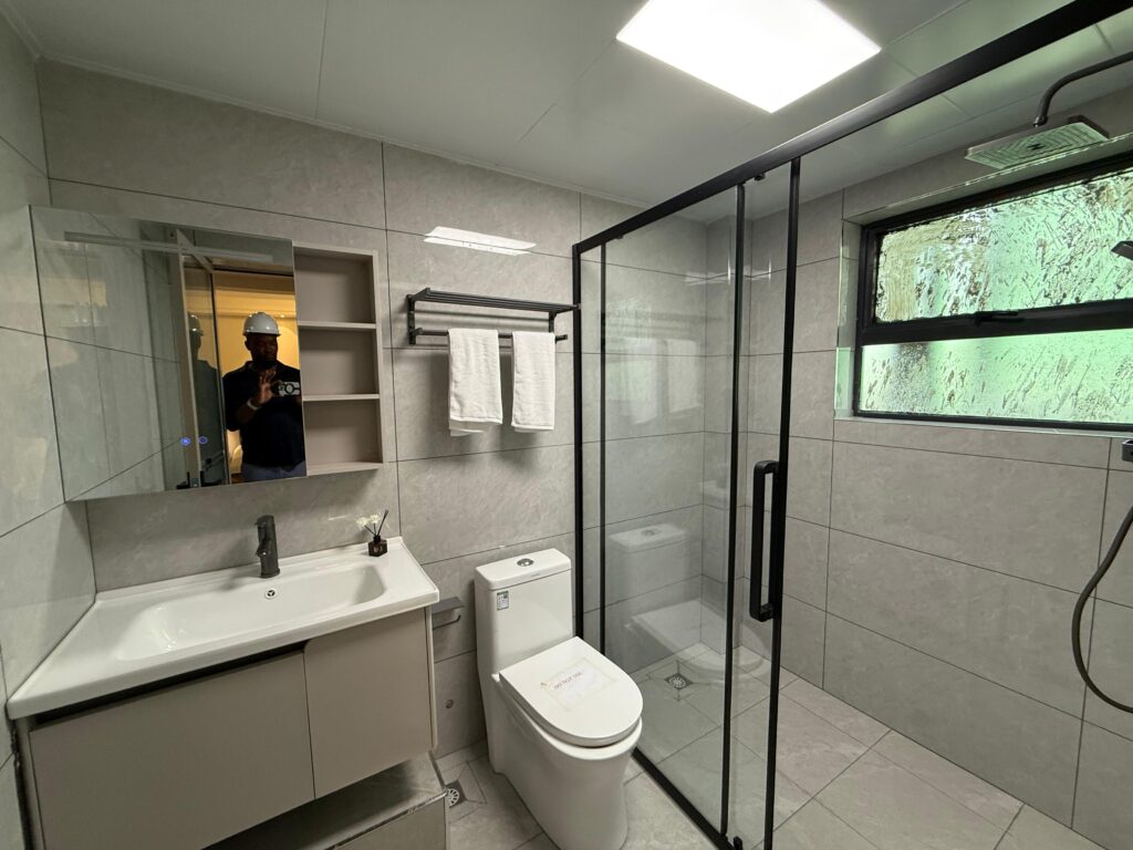 bathroom with glass showers,a toilet and a sink with a mirror at the Two Bedroom Apartment Near Nyeri Road