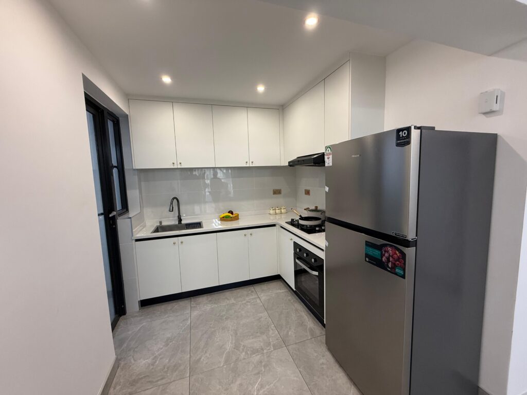 An open plan kitchen with fitted white cabinets and a cooker at Crescent Apartment Kileleshwa 2 bedroom a