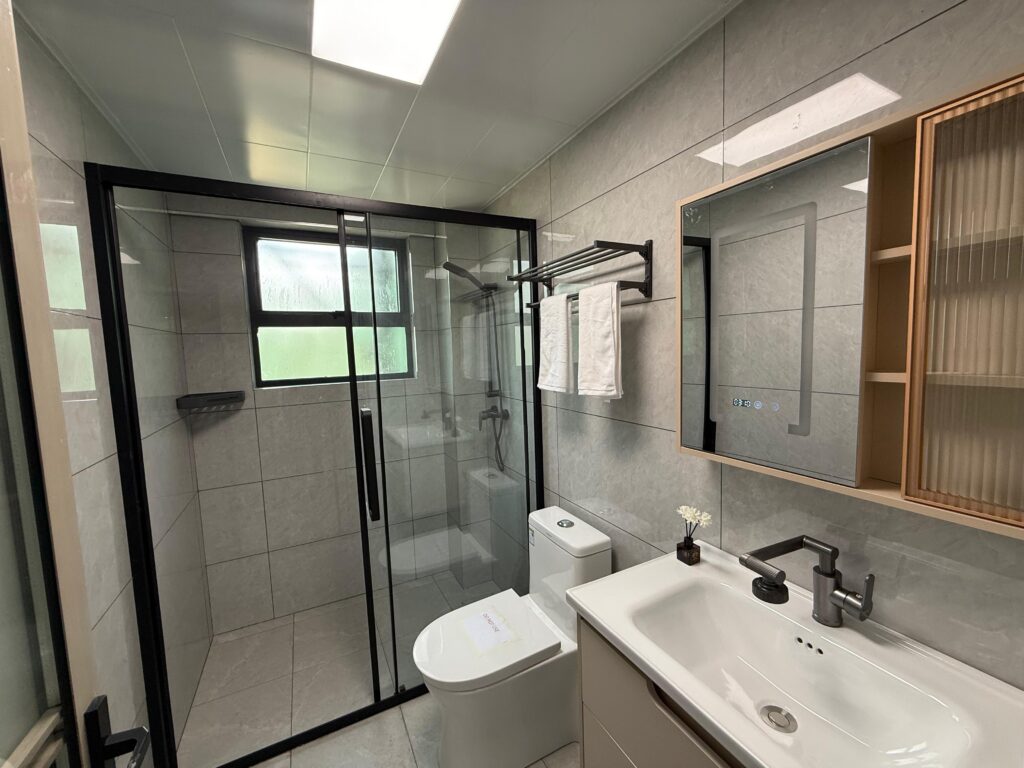 Bathrroom with glass cubicle shower, a toilet and a sink with a mirror at Crescent Apartment Kileleshwa 2 bedroom