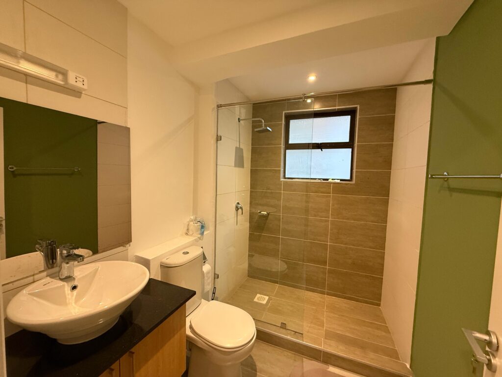 A bathroom with glass shoers, a toilet and a sink with a mirror inside the Furnished Apartment At Jade