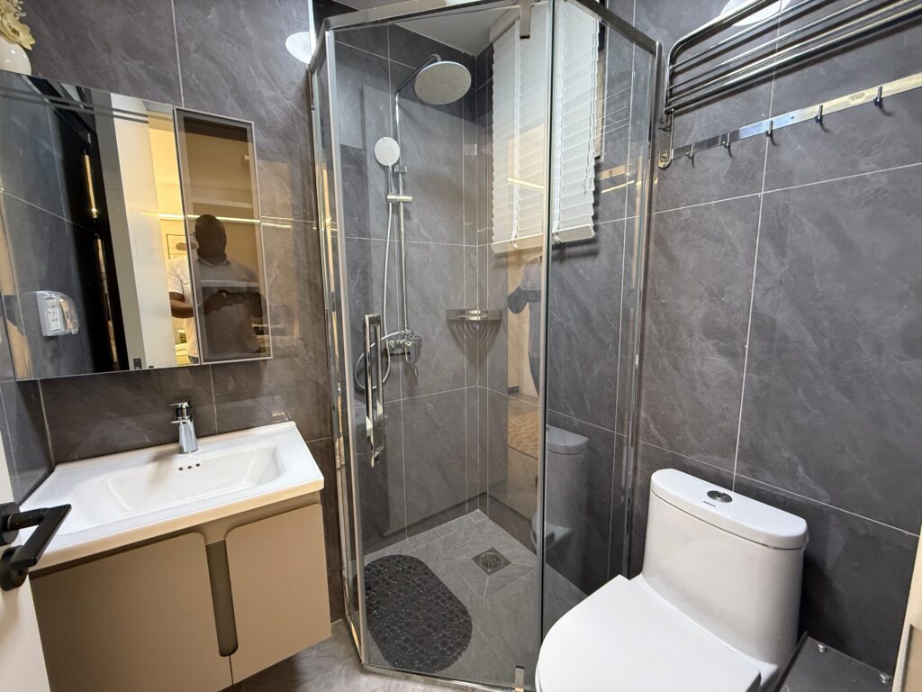 A bathroom with cubicle glass shower , a toilet and a sink with a mirror at Two Bedroom Apartment on Wood Avenue